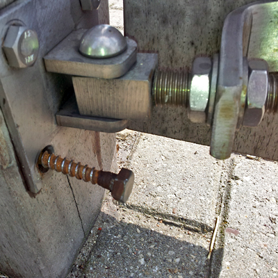 Close-up van een scharnier van het hek met een verroeste schroefbout.